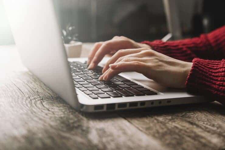 Woman typing on a silver laptop
