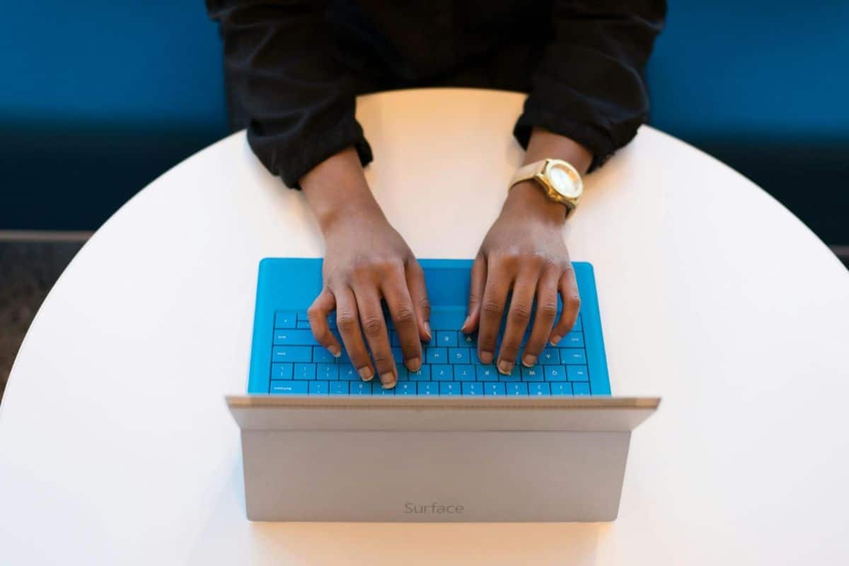Close-up of a Black American woman's hands typing on a laptop keyboard