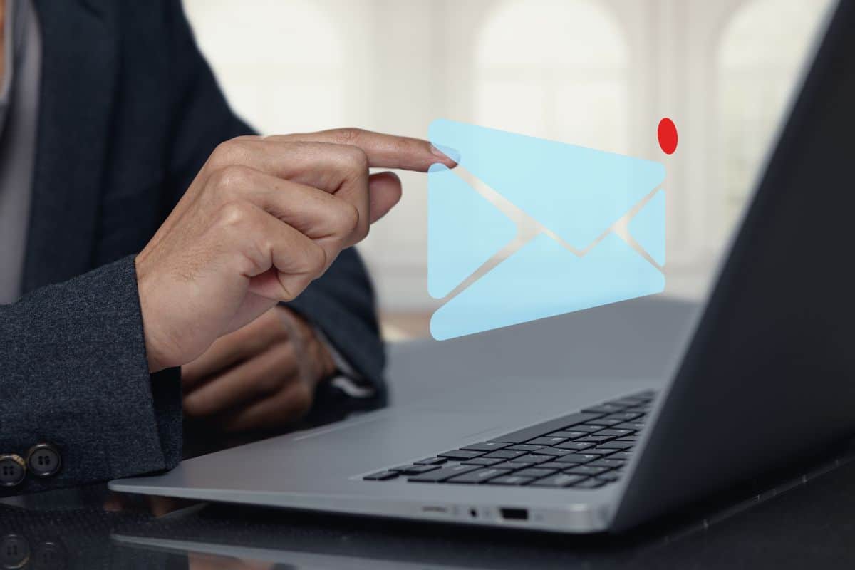 Person interacting with email icon on laptop in modern office