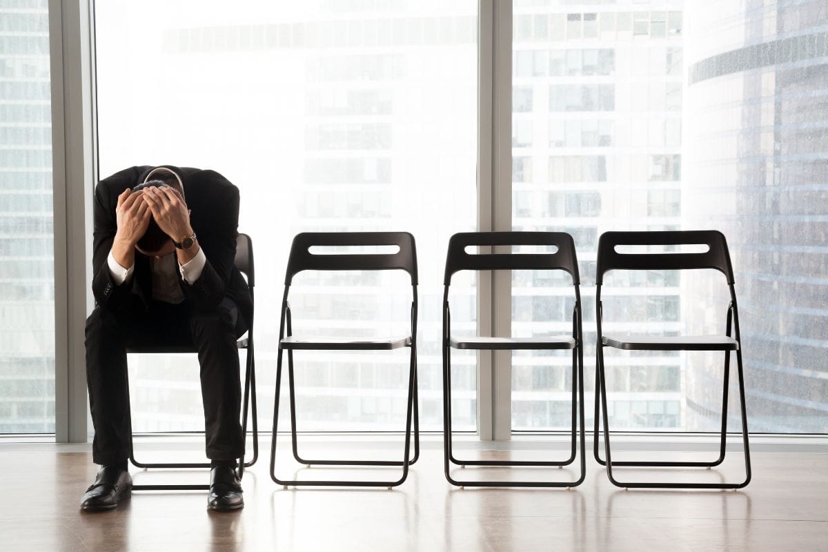 Stressed upset businessman sitting on chair in waiting room