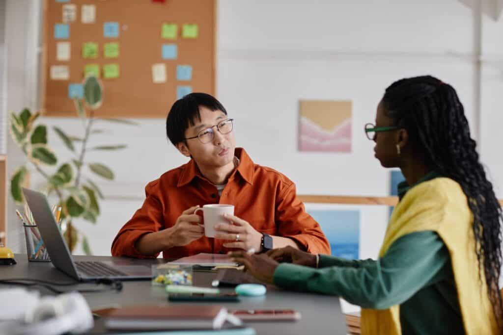 Las mejores aptitudes para un currículum y cómo destacarlas 8 Conversing in modern office setting near a desk