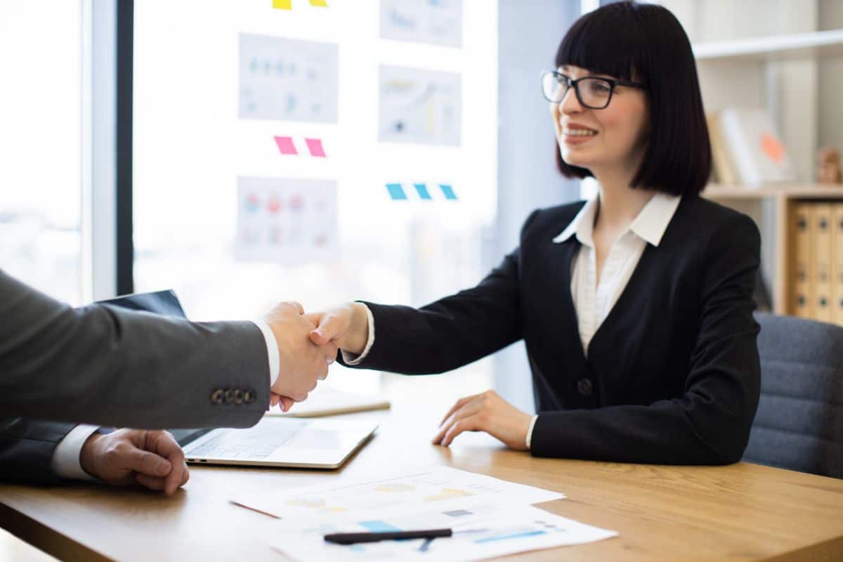 Business woman shaking hands with colleague in modern office setting