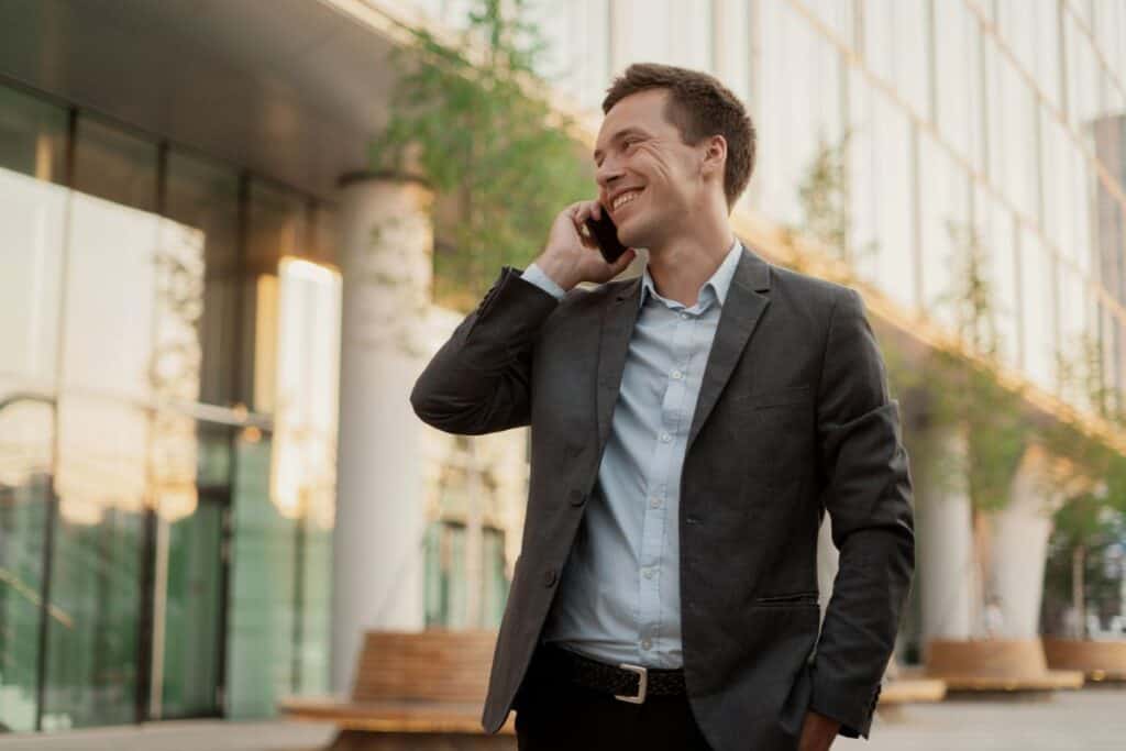 Wie man ein Stellenangebot annimmt: Tipps für E-Mail, Anruf und Brief 5 A manager in a business suit uses a phone the financier goes to work