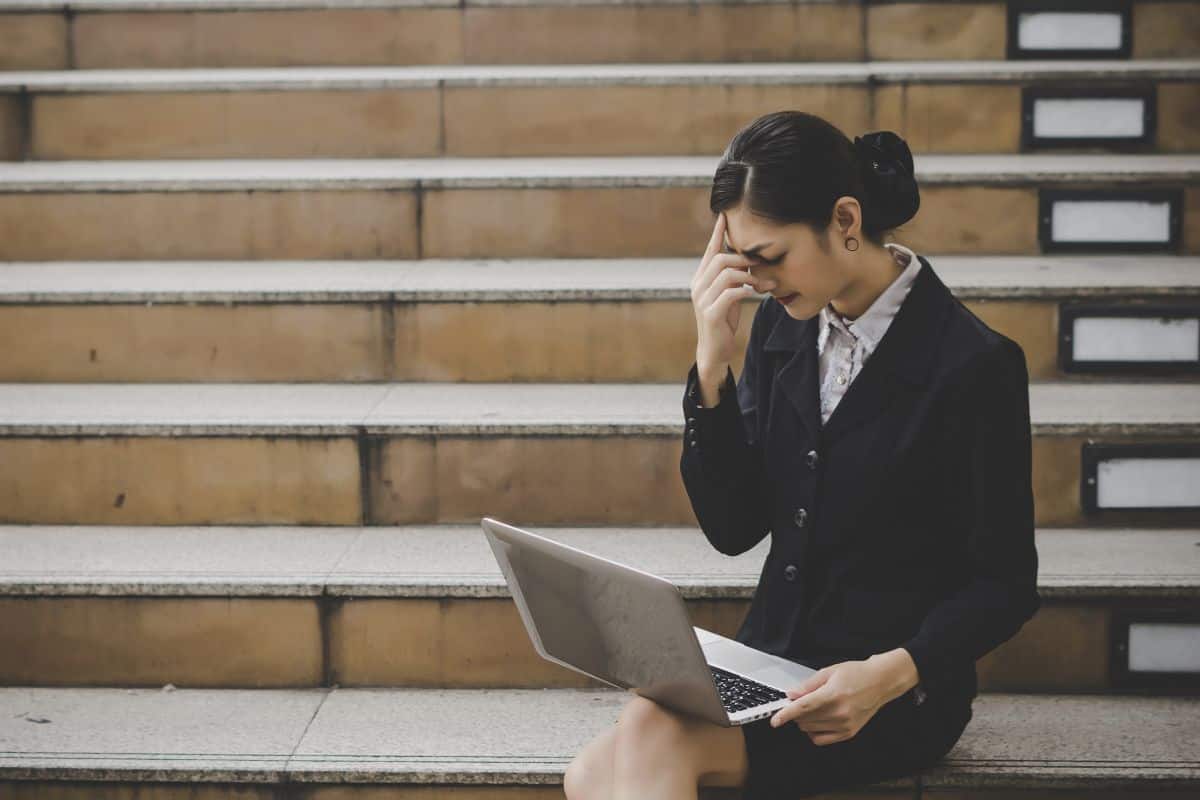 Young woman sitting on staircase using laptop computer