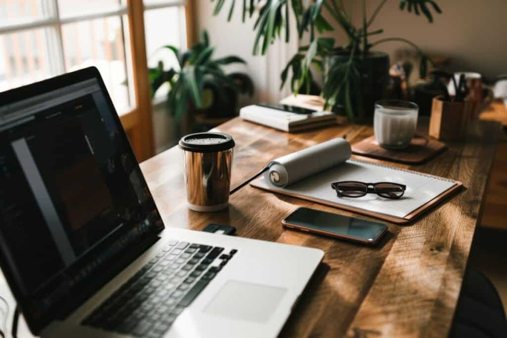 A creative workspace with a laptop coffee sunglasses and plants