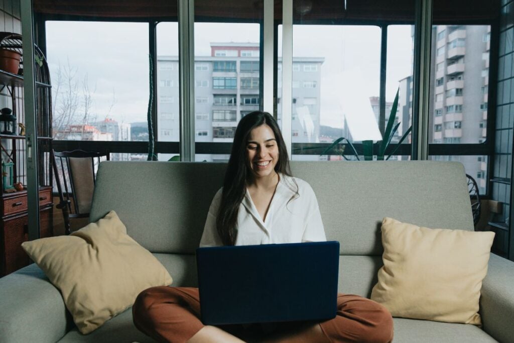 Woman working on his laptop while smiling from home during the pandemic