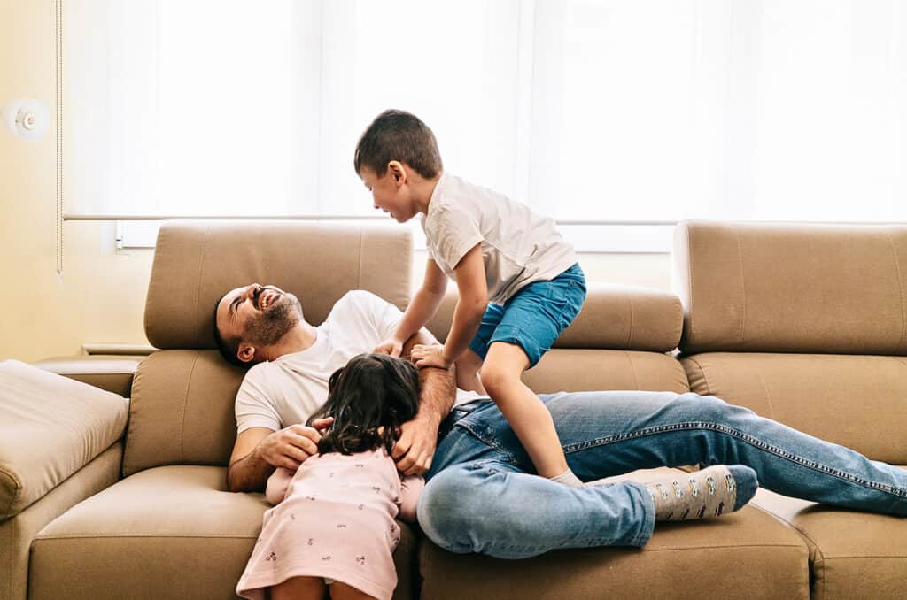 Father bonding with his son and daughter on the couch, sharing a warm family moment