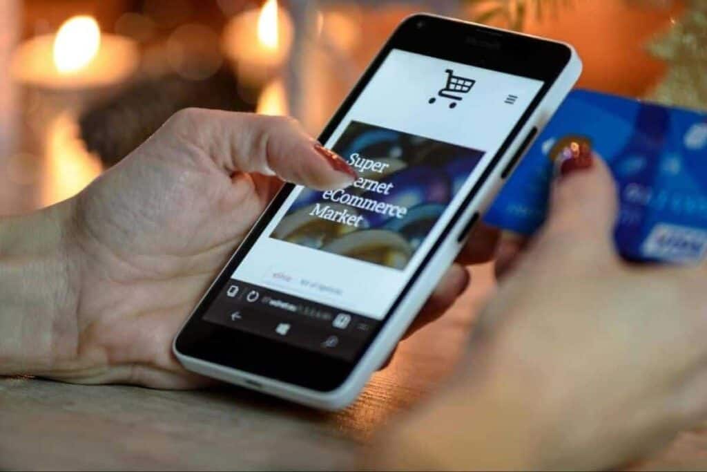 Imagen de archivo de una mujer con un teléfono inteligente y una tarjeta de crédito, haciendo una compra en línea