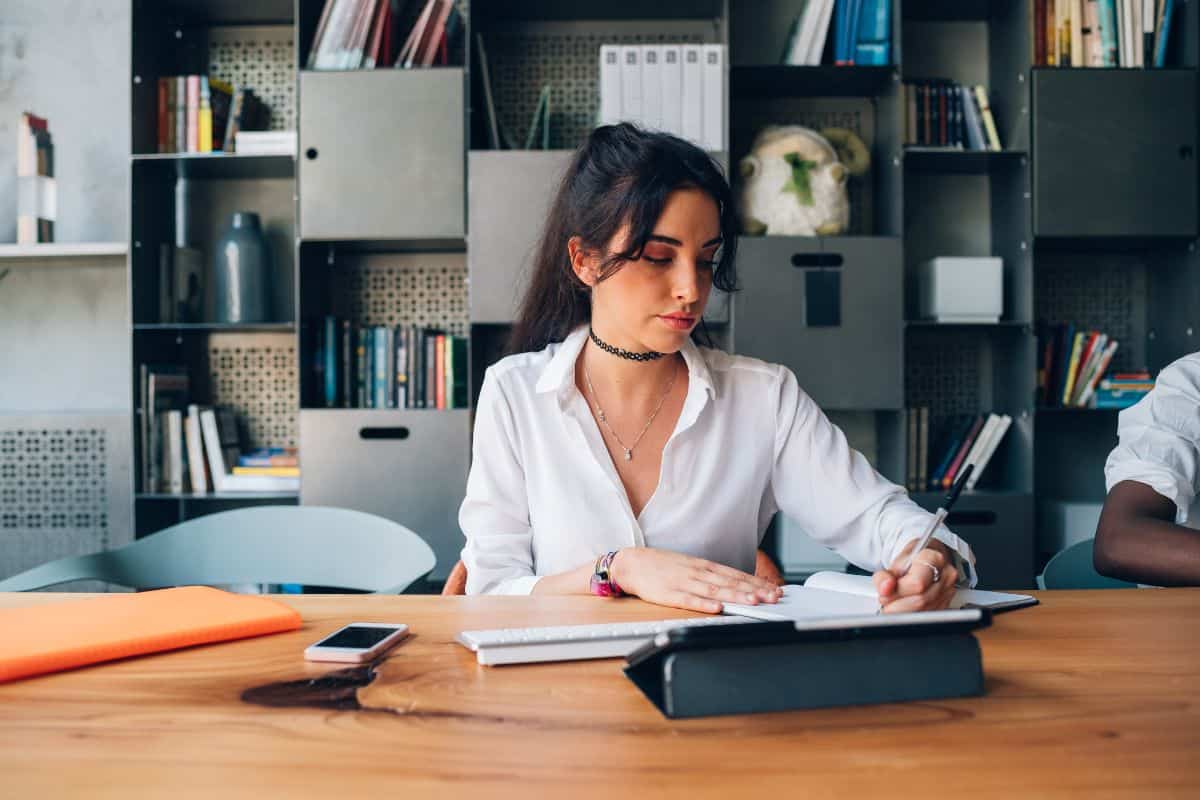 Young woman writing during meeting in modern office