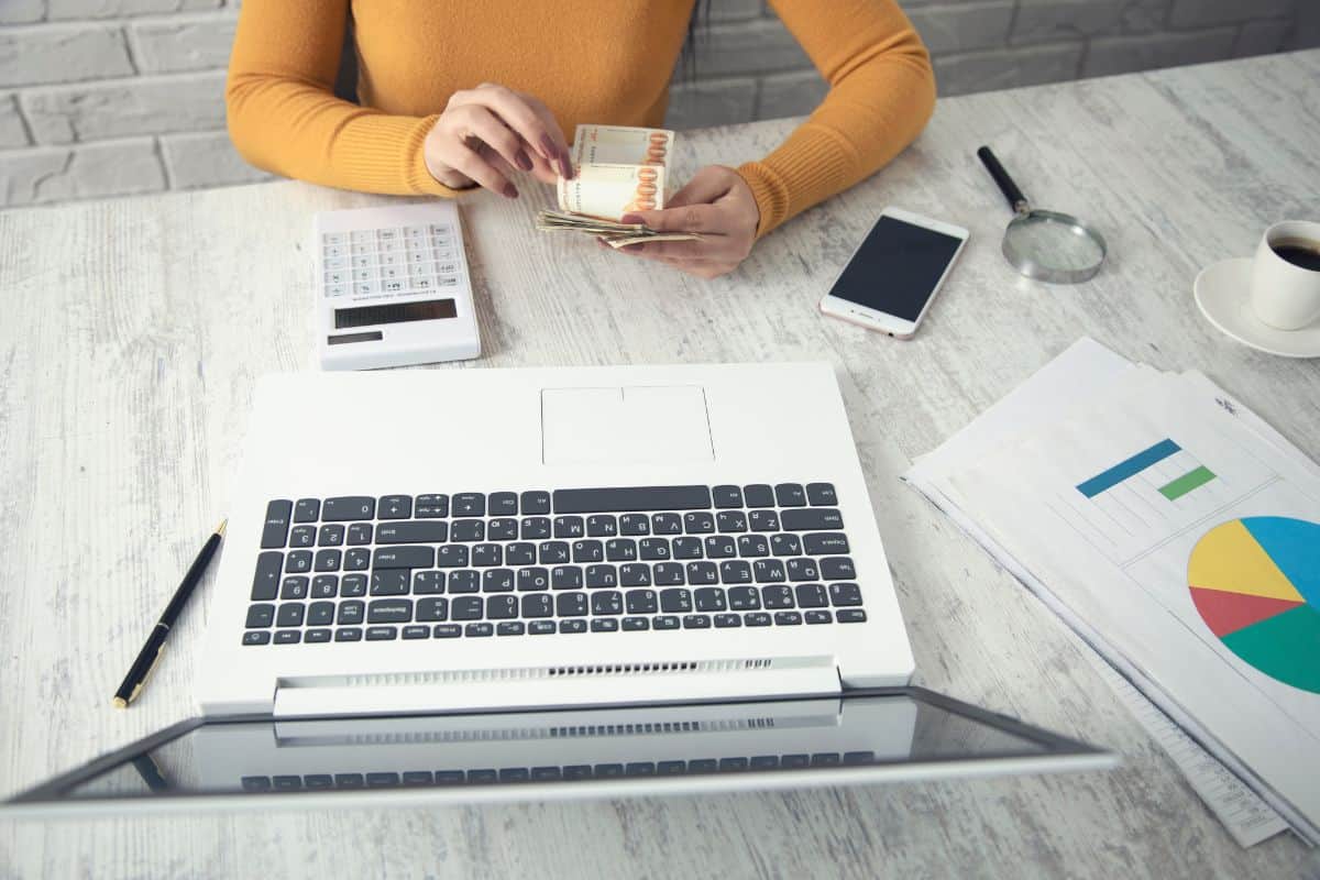 Business woman using calculator and holding money