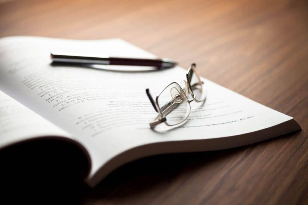 Comment titrer un essai (de la bonne façon) 4 Reading glasses, pen and open book