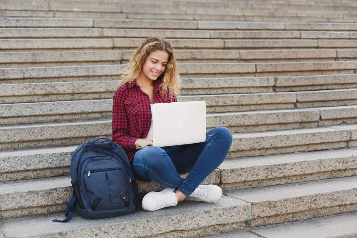 Young beautiful student sitting on the stairs outdoors