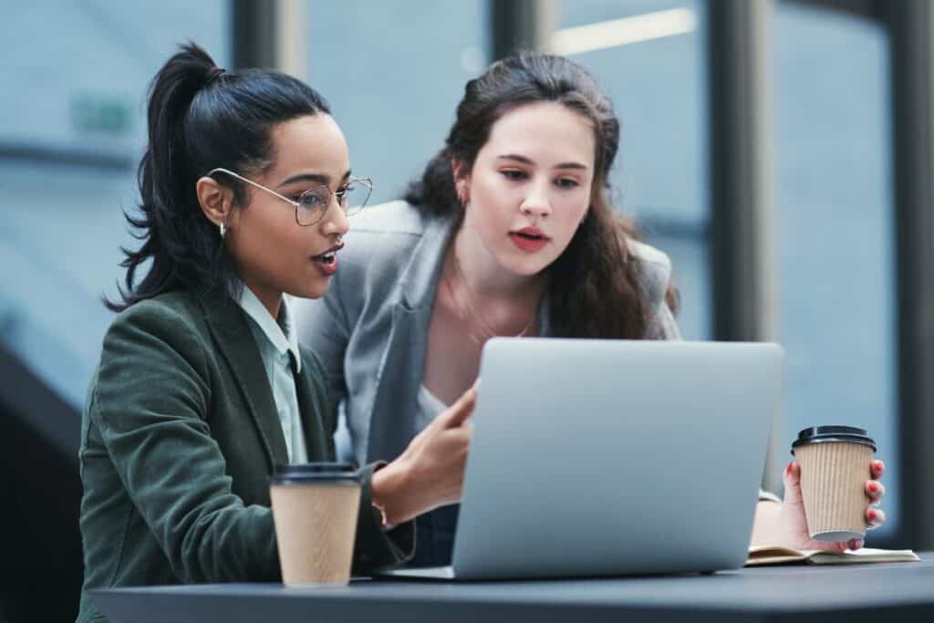 Business women talking and laptop meeting at coffee shop