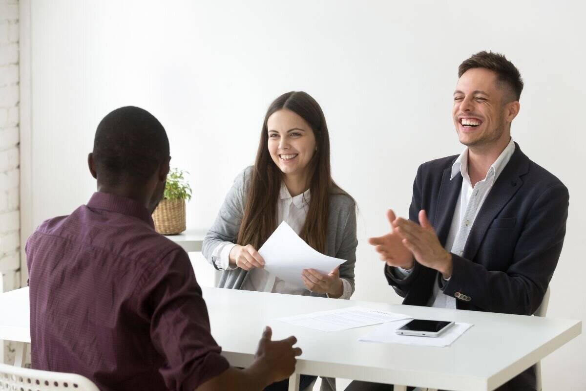 Deux recruteurs interviewant un homme africain, se livrant à une séance professionnelle de questions-réponses.