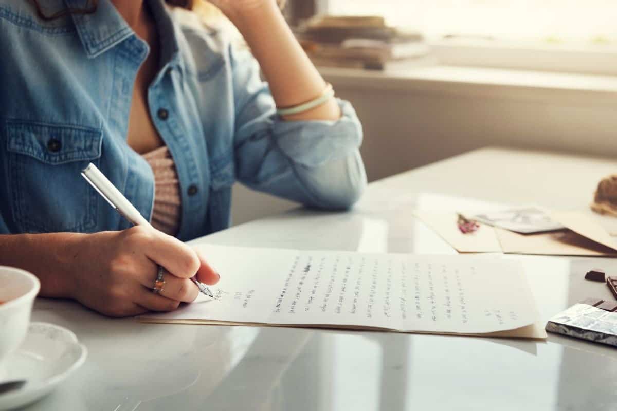Mujer escribiendo un ensayo, centrada en organizar sus pensamientos y componer un contenido estructurado.