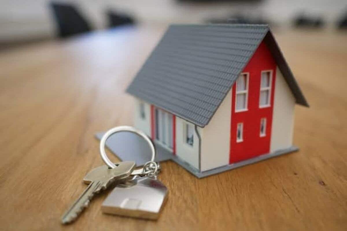 Stockbild eines Miniaturhauses neben einem Schlüssel, der Immobilien symbolisiert