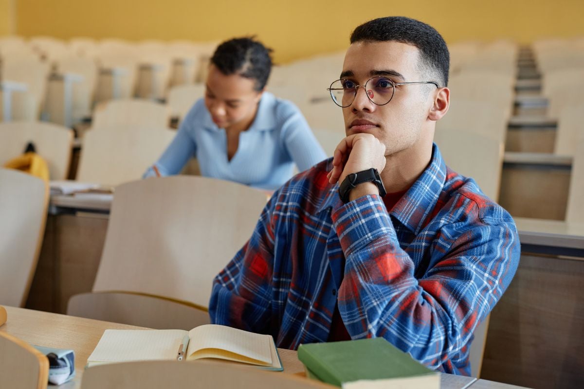 Teenage boy in eyeglasses sitting at desk