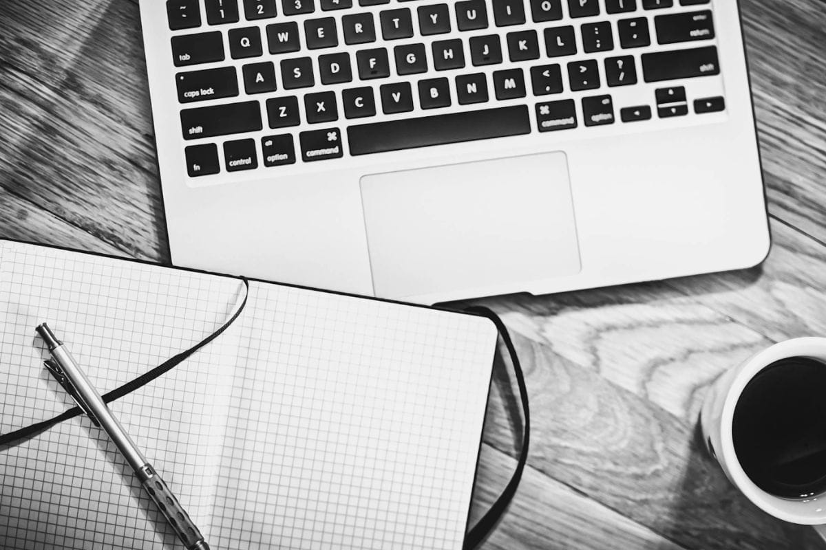 Un ordinateur portable sur un bureau avec un cahier placé à côté.