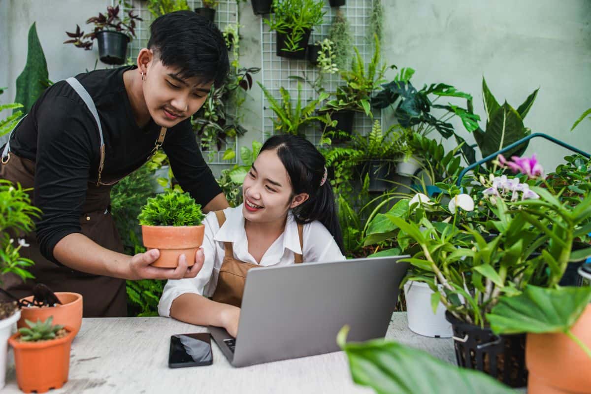 Stock image of two young men and a woman surrounded by plants