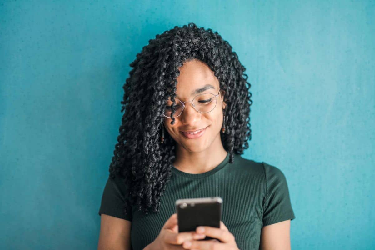 Eine schwarze Frau, die mit konzentrierter Miene auf ihr Telefon schaut.