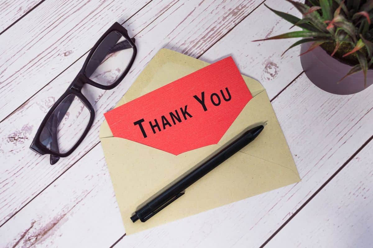 Thank you text on red card with envelope on wooden desk
