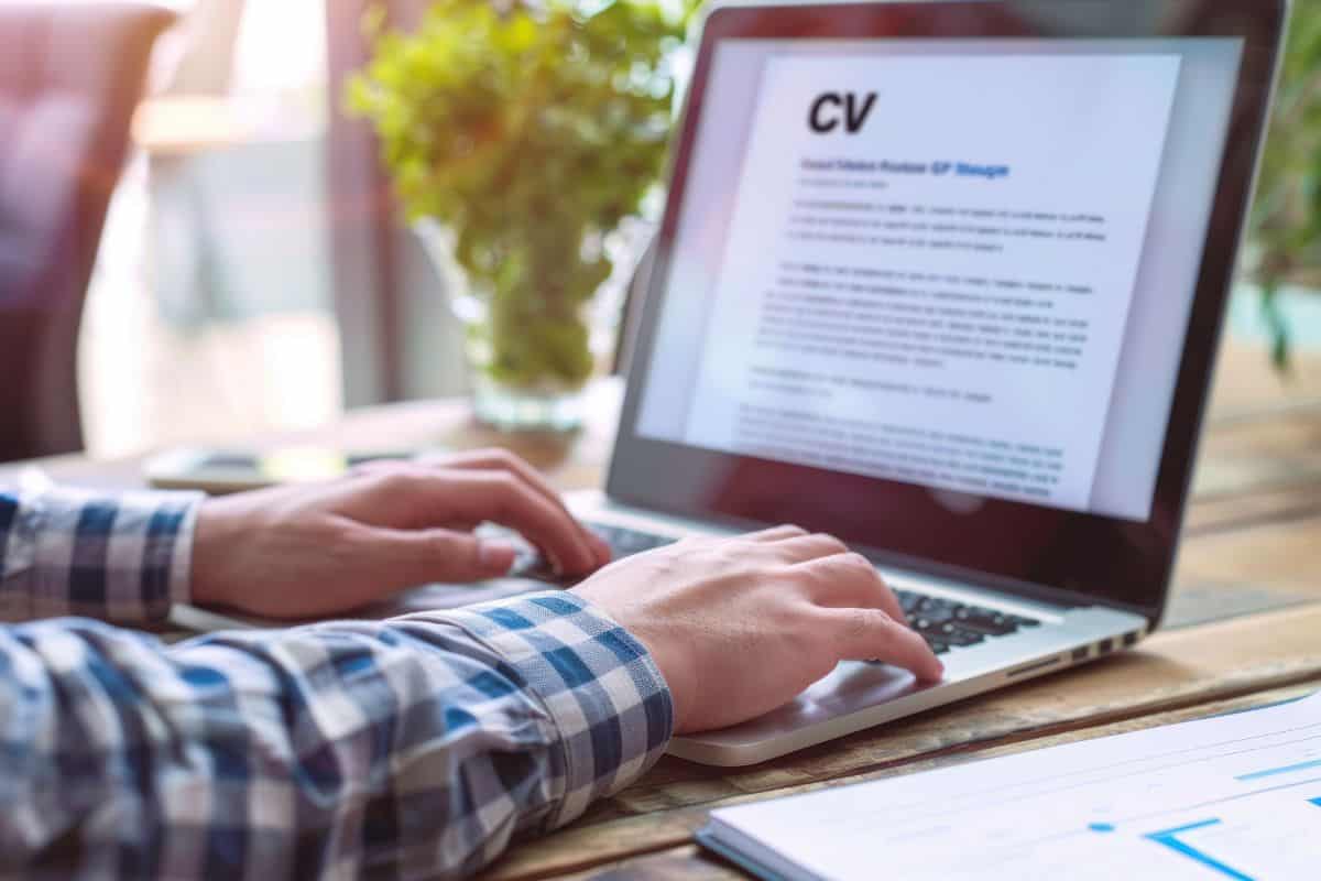 Person typing a cv on a laptop at a desk office workspace