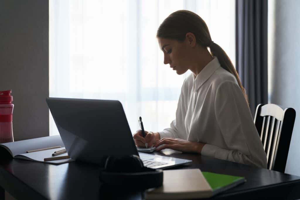 Comment utiliser ChatGPT pour gagner de l'argent : Méthodes éprouvées 5 Focused woman sitting at table and working on laptop