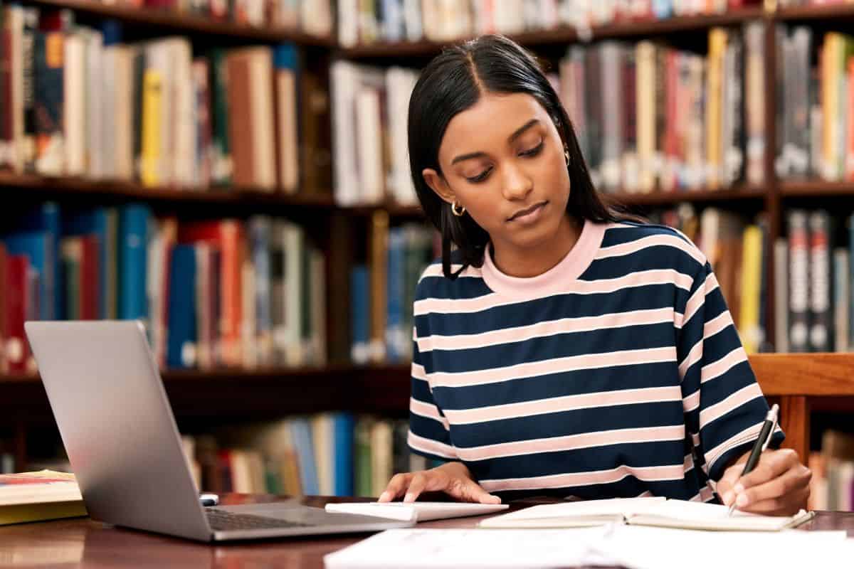 Student laptop and girl in library writing