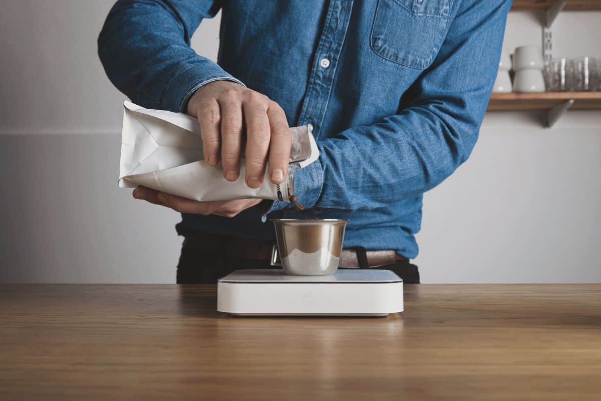 Préparation pas à pas d'un café à l'aide d'une presse à café, barista en chemise de jeans bleu.