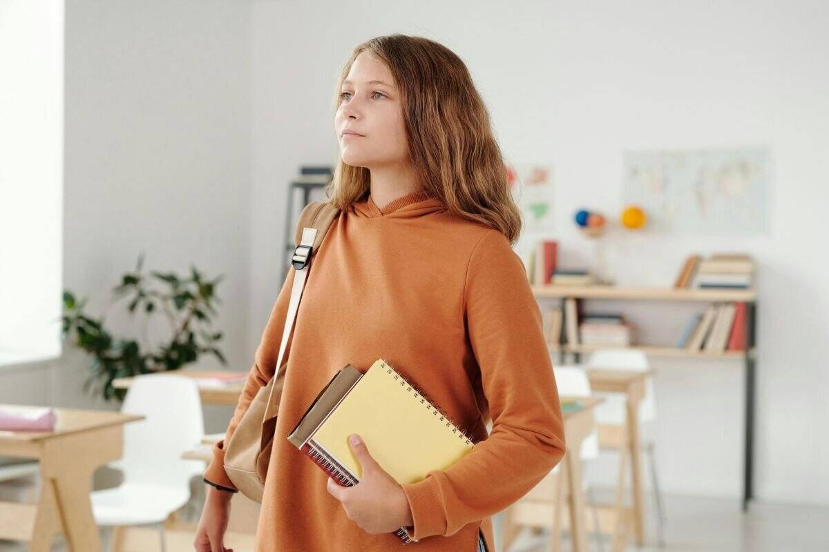 Donna con maglione marrone che trasporta libri