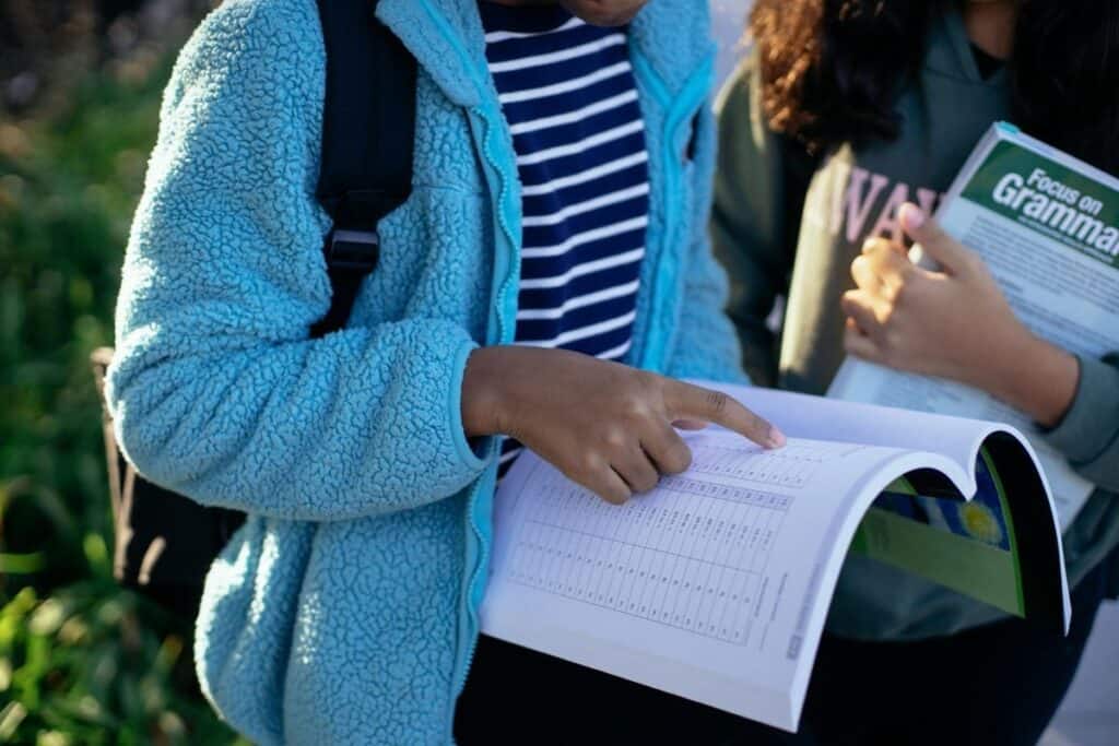 ¿Qué son las preposiciones? Guía gramatical + Ejemplos 6 Escolares de minorías étnicas comparten cuaderno de ejercicios en una calle brillante