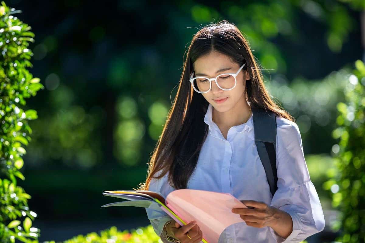 Stock image of a girl studying while walking