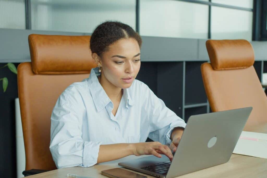 A focused young woman working on a laptop in a modern office environment