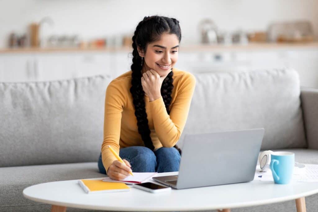 Distant learning smiling indian woman using laptop at home