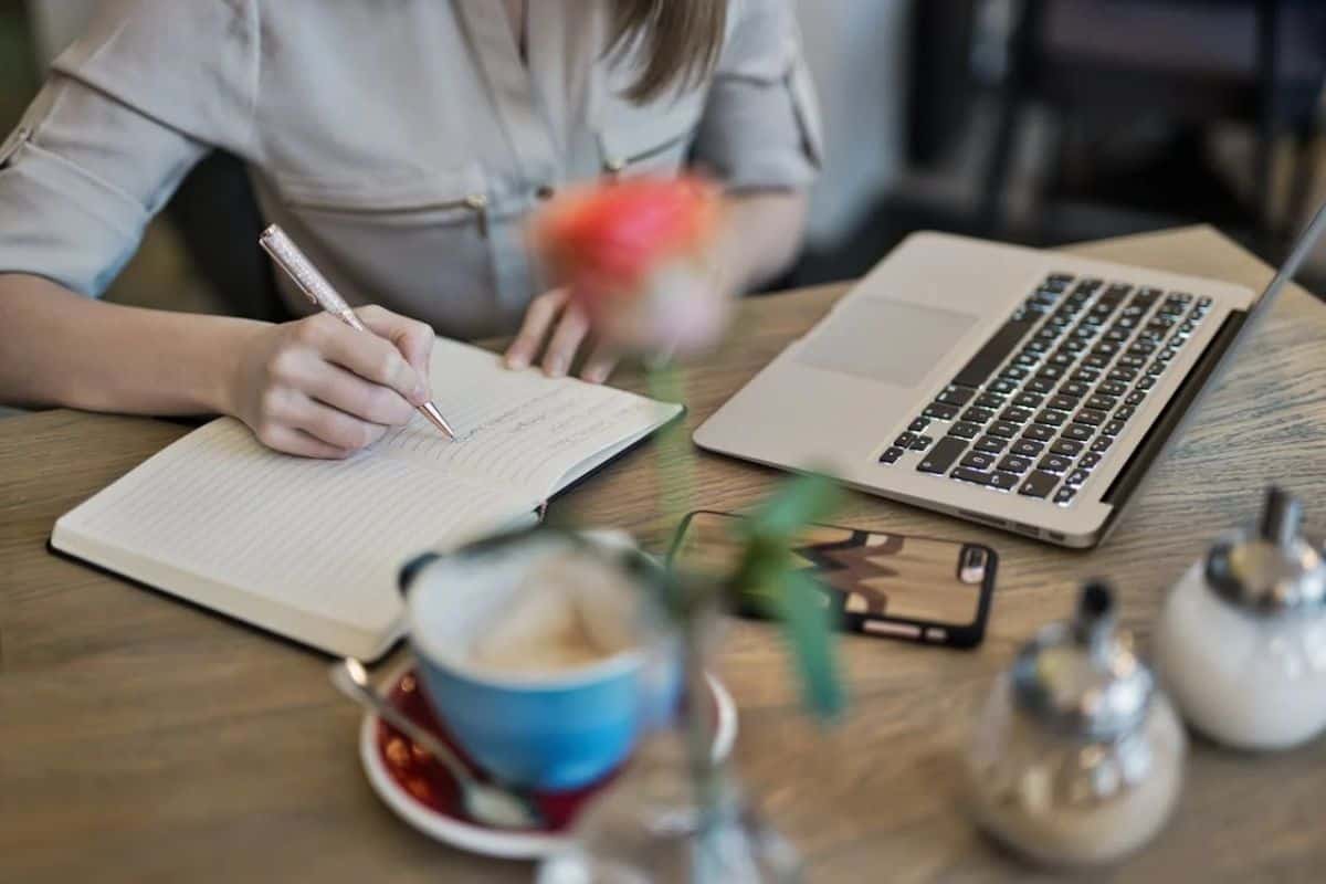 Woman writing in a notebook at a coffee shop