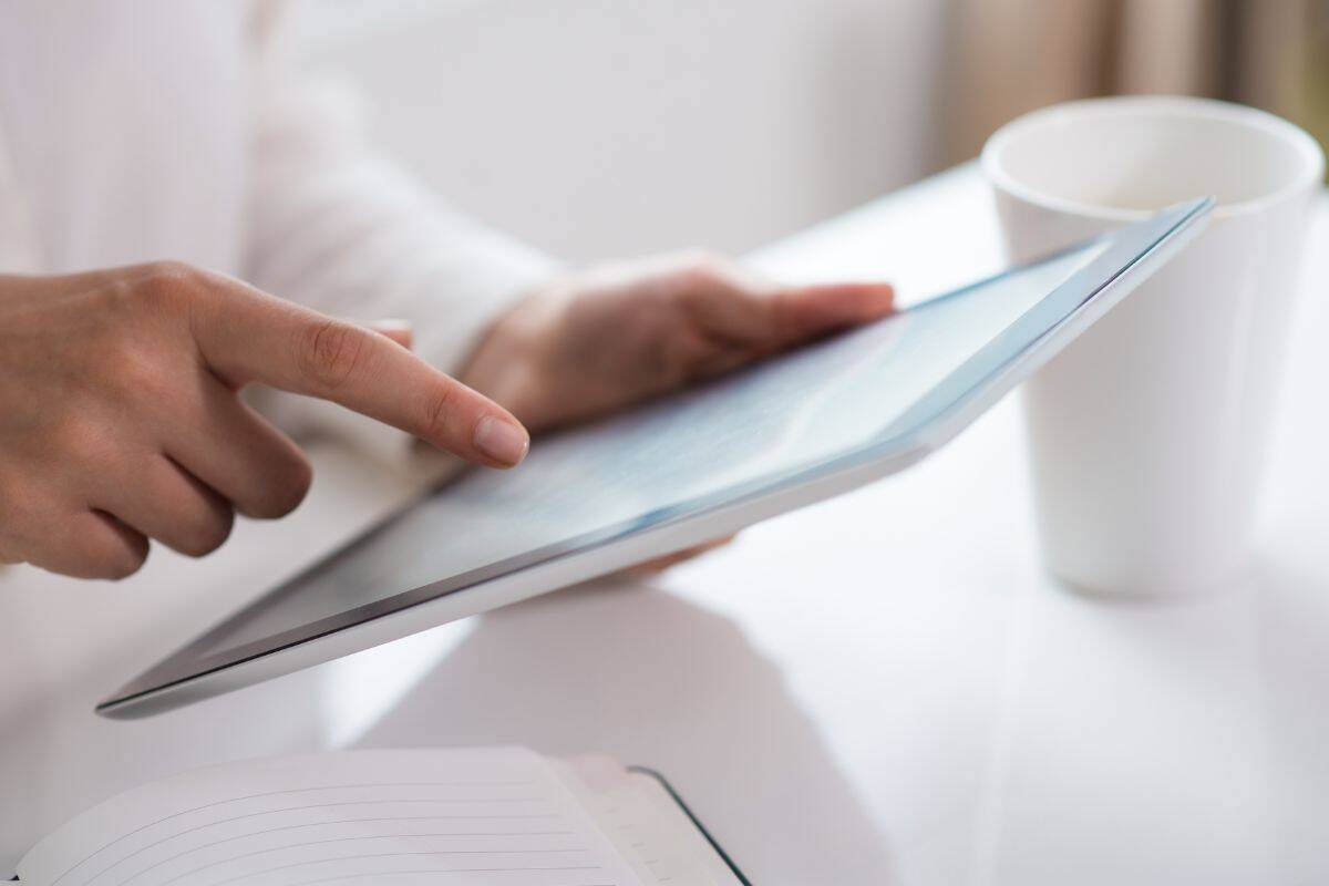 Gros plan de la main d'une femme utilisant une tablette numérique.