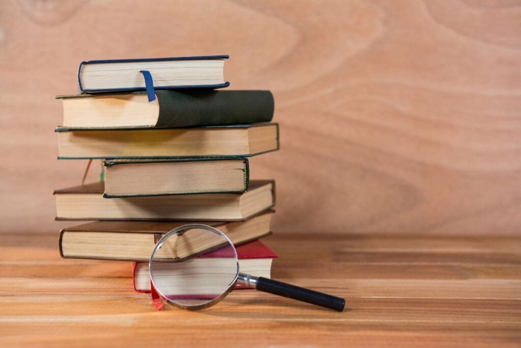 Vergrößerungsglas mit Bücherstapel auf einem Tisch