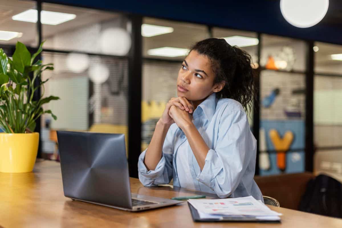 Femme pensive au bureau avec un ordinateur portable