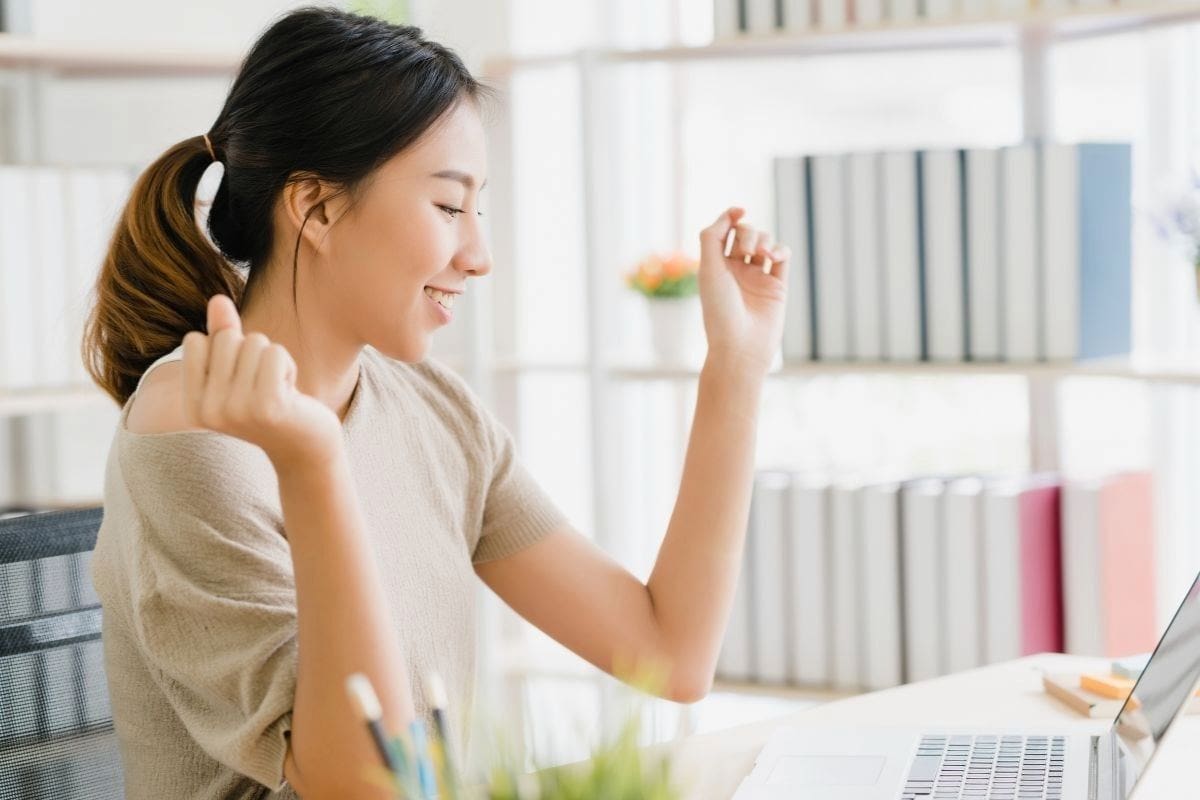Beautiful young smiling asian woman working laptop on desk