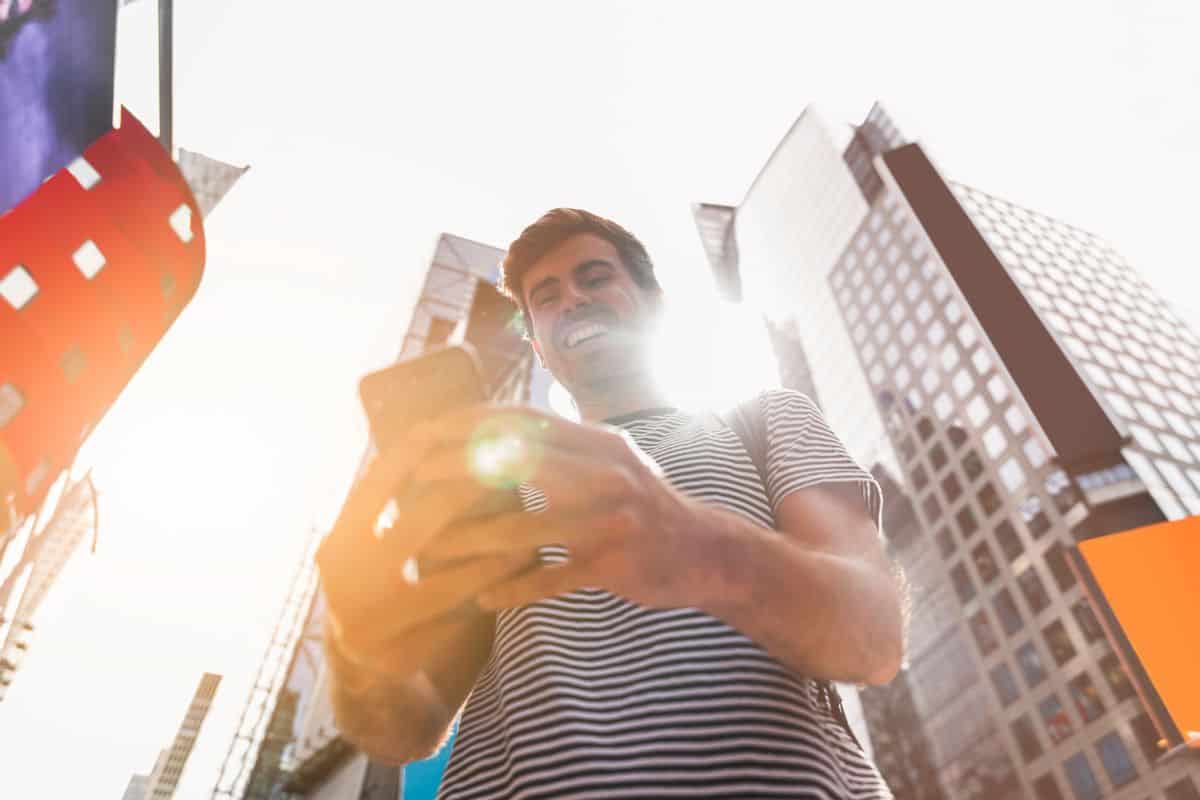 Junger Mann lächelt, während er sein Smartphone benutzt