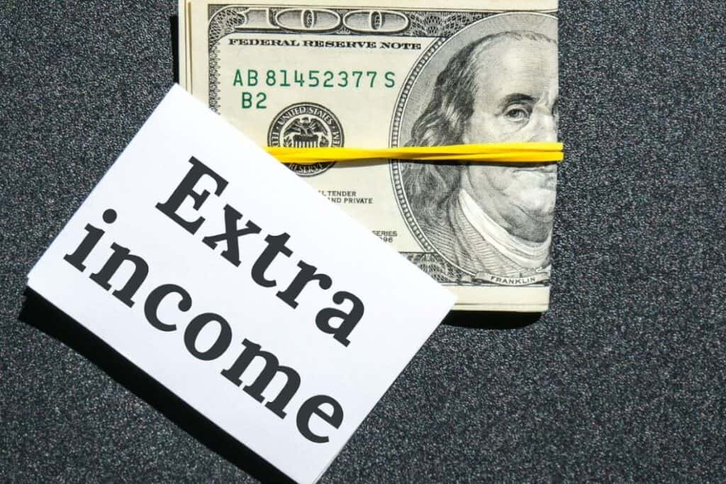 Extra income written on paper with folded money behind it