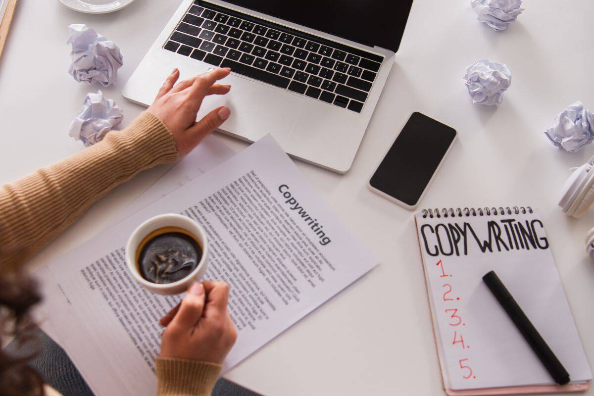 Top view of copywriter holding coffee and using laptop