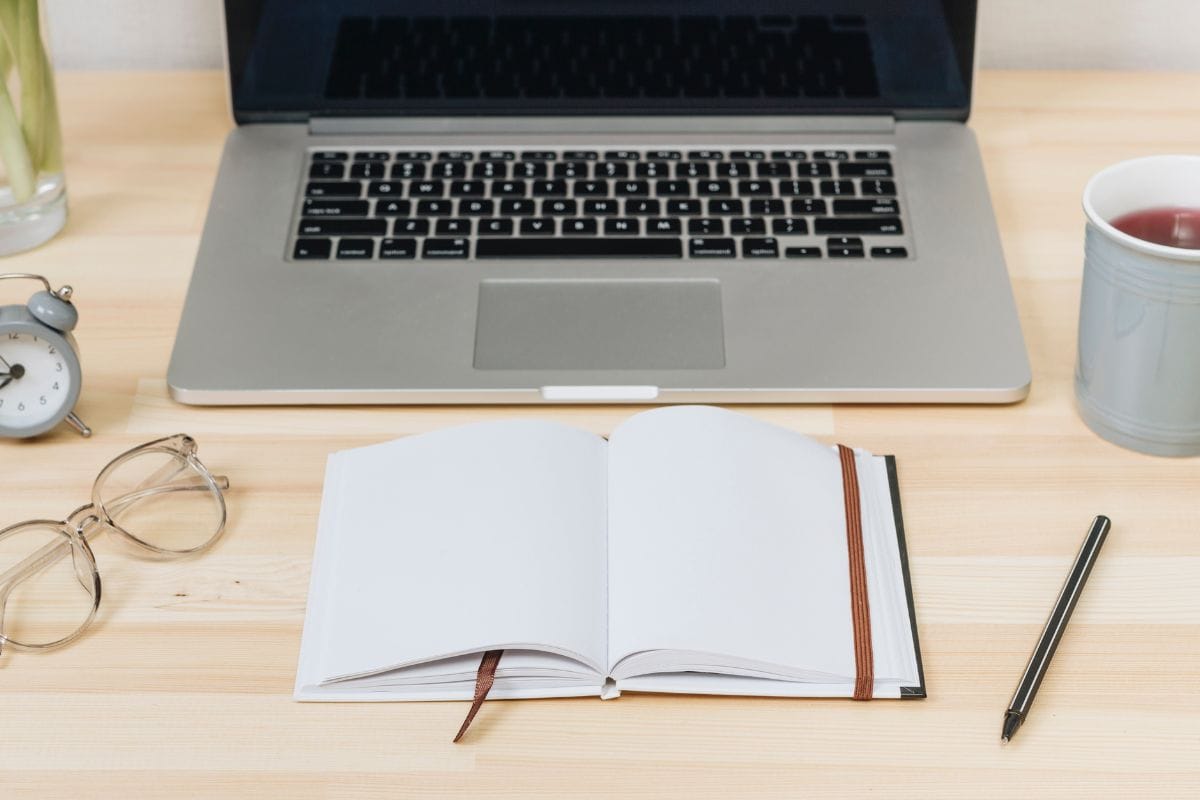 Laptop with notebook on wooden table