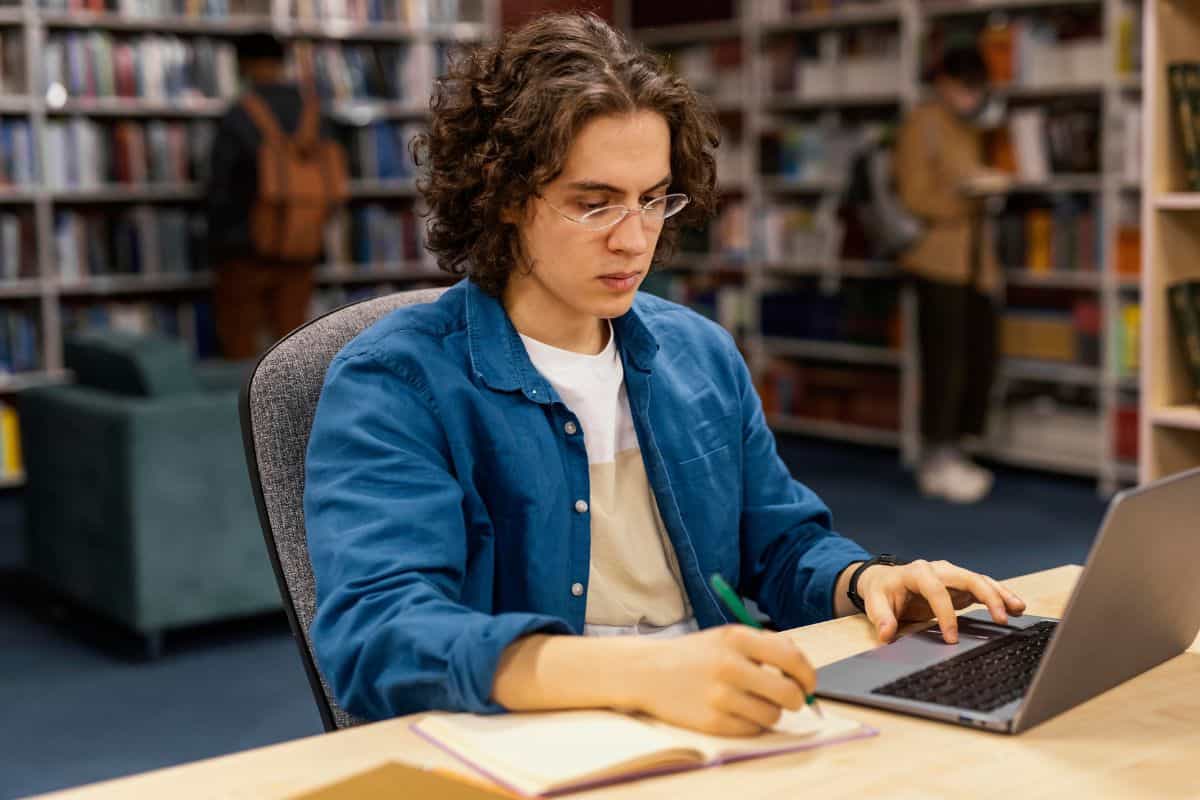 Rapaz estudando na biblioteca da universidade