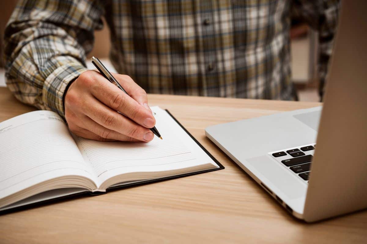 Casual man writing in blank notebook