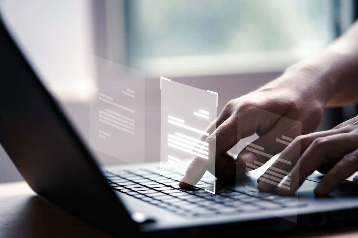 Mano utilizando un ordenador portátil con pantalla virtual y documento.