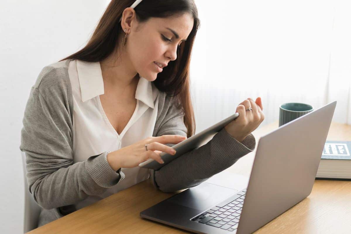 Plan moyen : femme travaillant à domicile sur une tablette