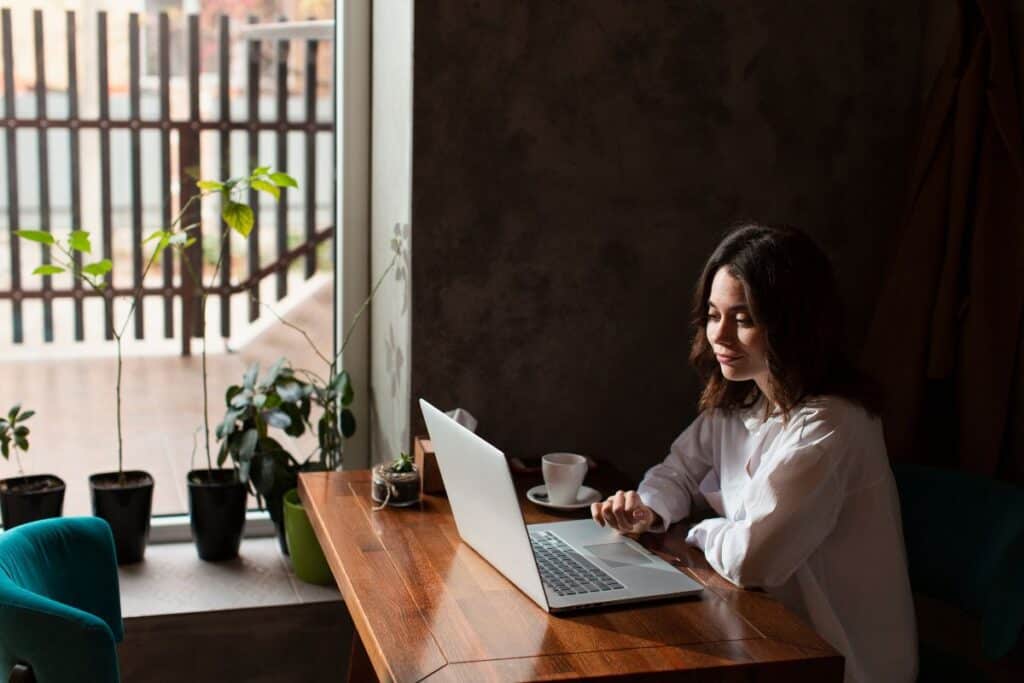 Frau in einem Café, die an ihrem Laptop arbeitet