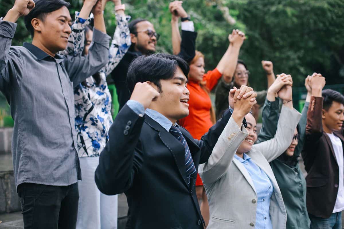 Happy colleagues celebrate corporate success or victory together outside