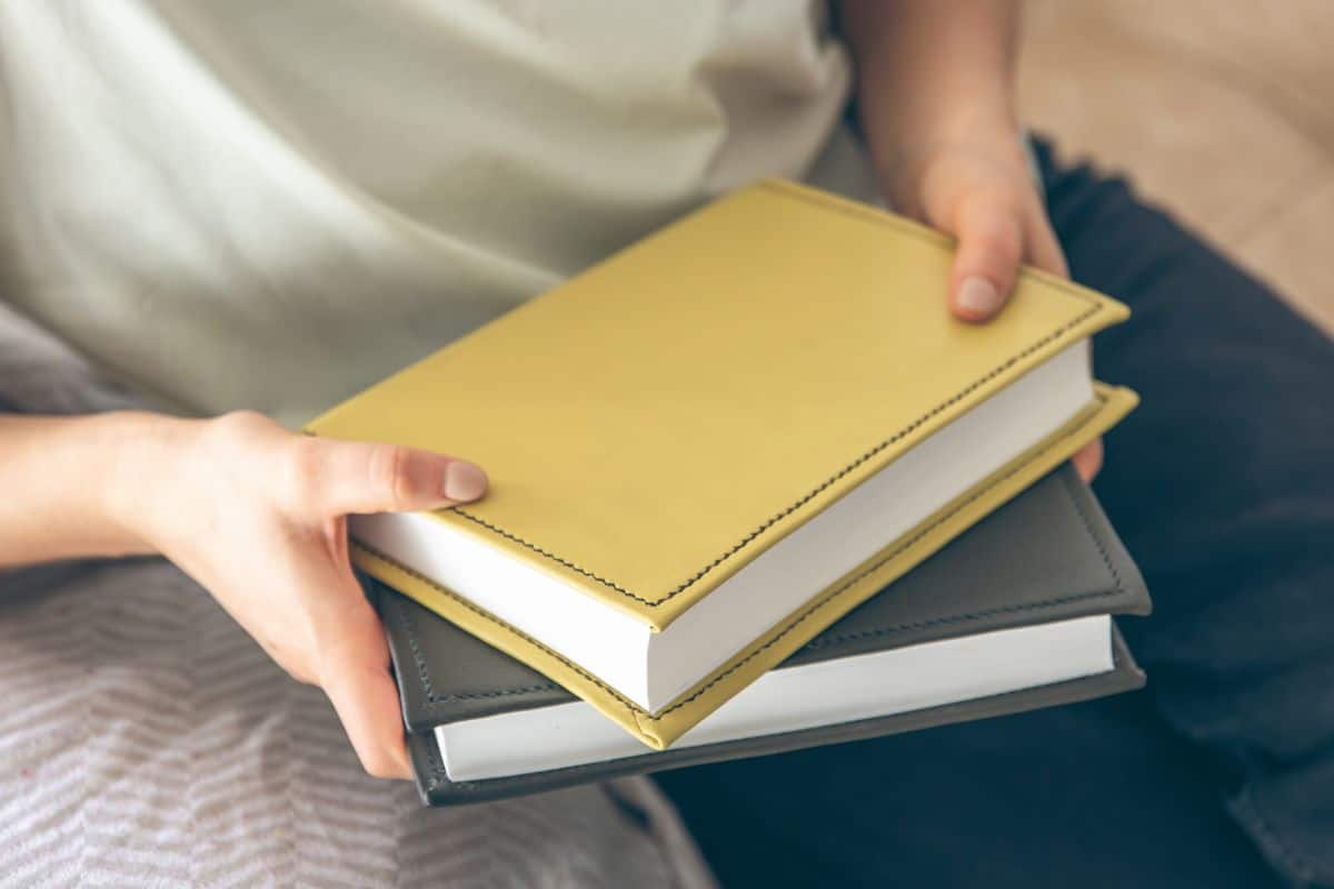 Eine Frau sitzt auf dem Sofa und hält Bücher in der Hand (Nahaufnahme)